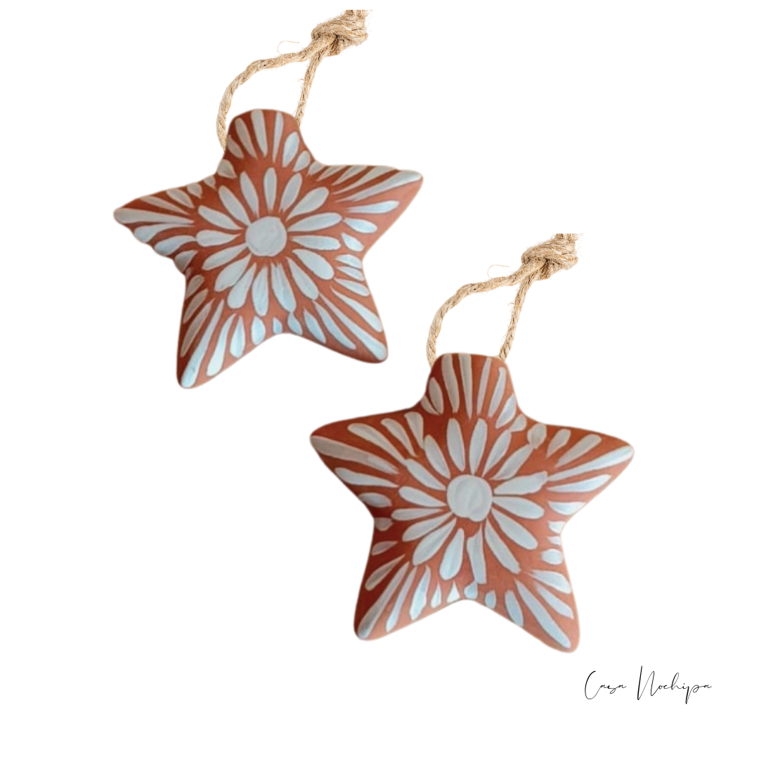 Estrella de barro terracota pintada a mano con flores blancas, ornamento navideño artesanal.