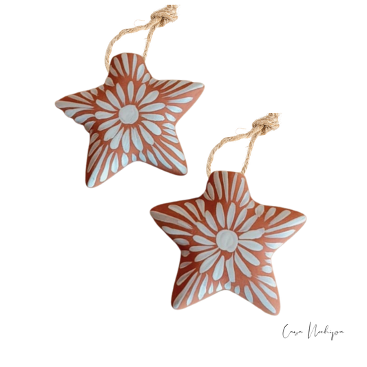 Estrella de barro terracota pintada a mano con flores blancas, ornamento navideño artesanal.