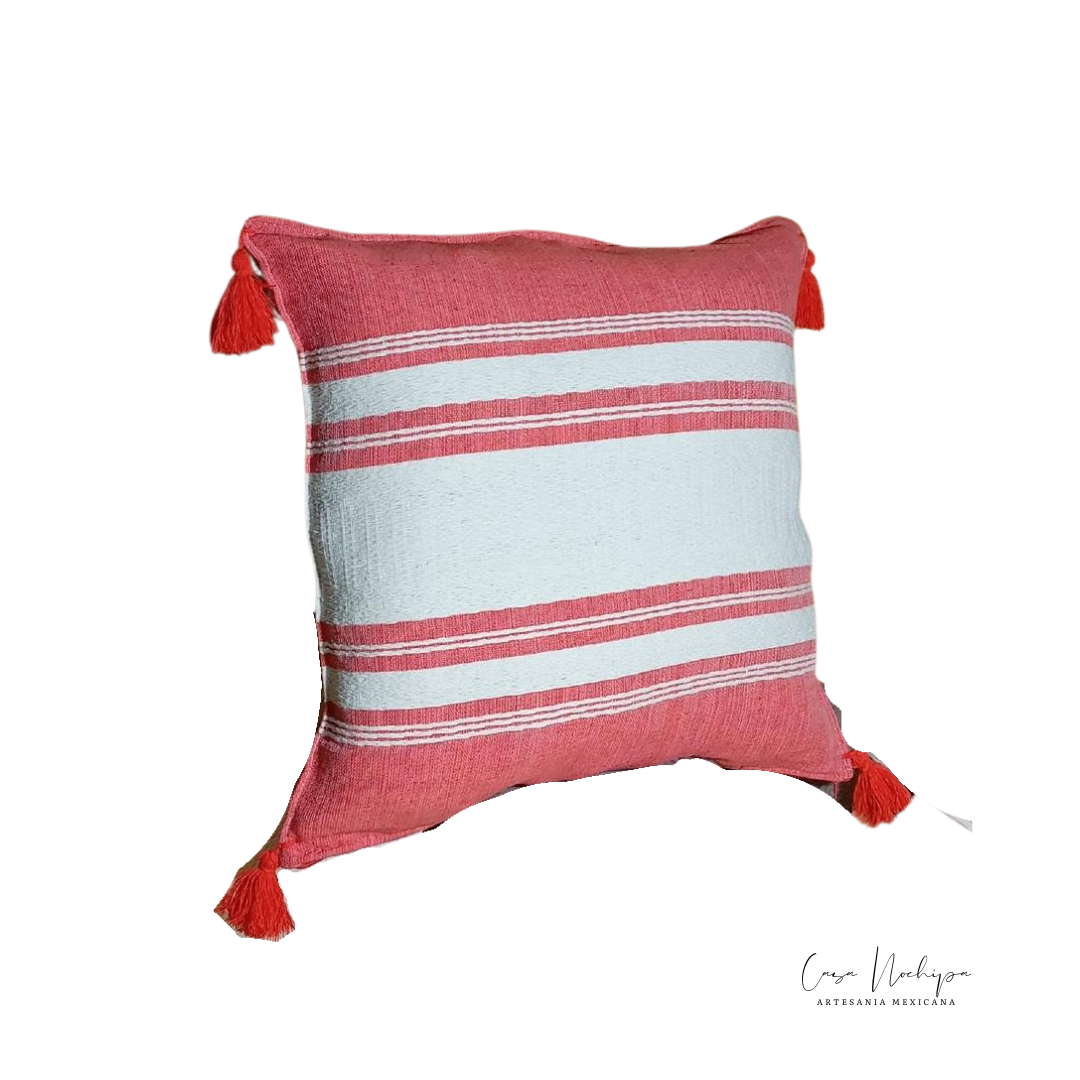 Cojín artesanal de algodón tejido en telar de pedal con detalles de borlas decorativas. Diseño mexicano elaborado a mano con materiales orgánicos.