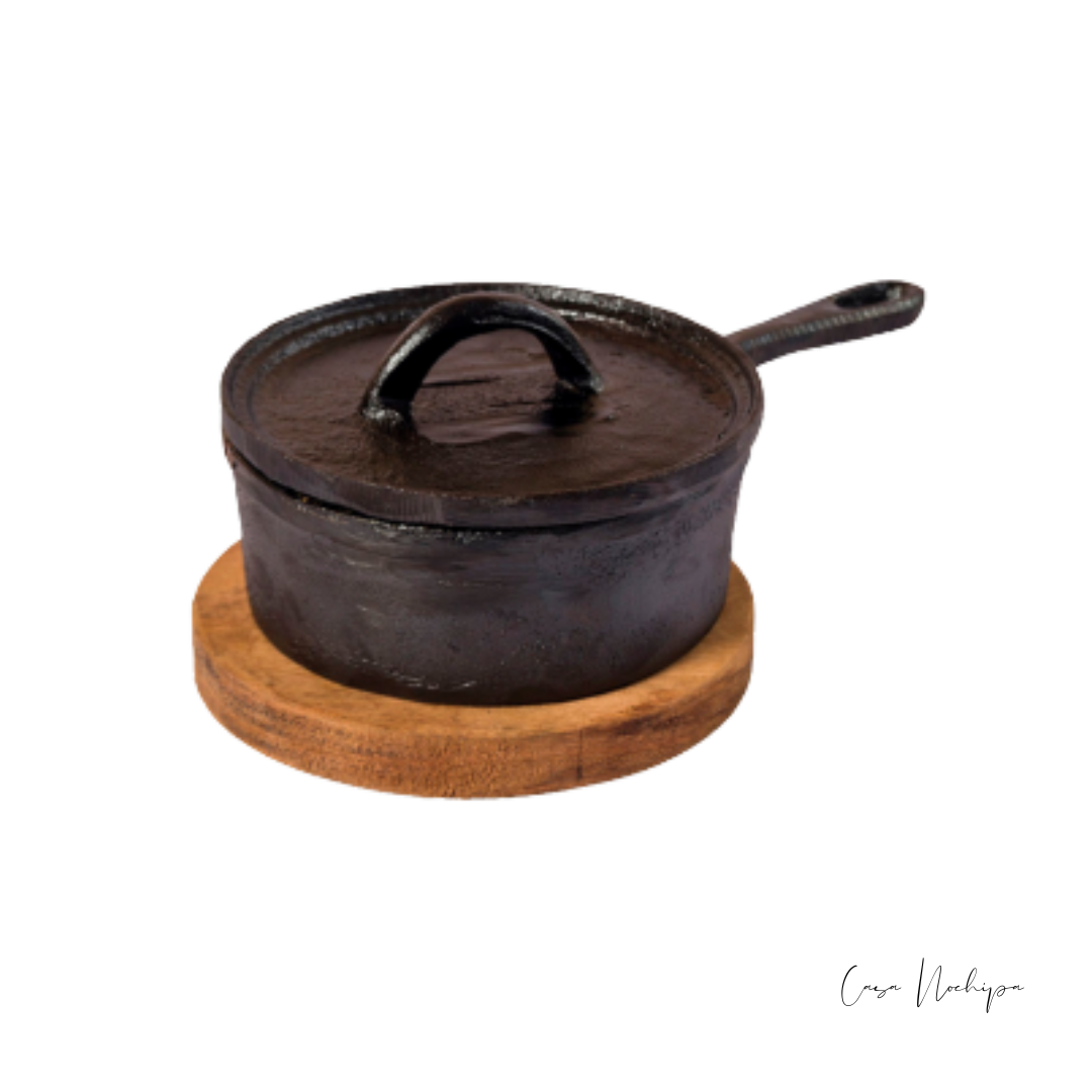 Cazuela de hierro fundido con base de madera de 15 cm, ideal para cocinar y servir con un estilo rústico y artesanal.