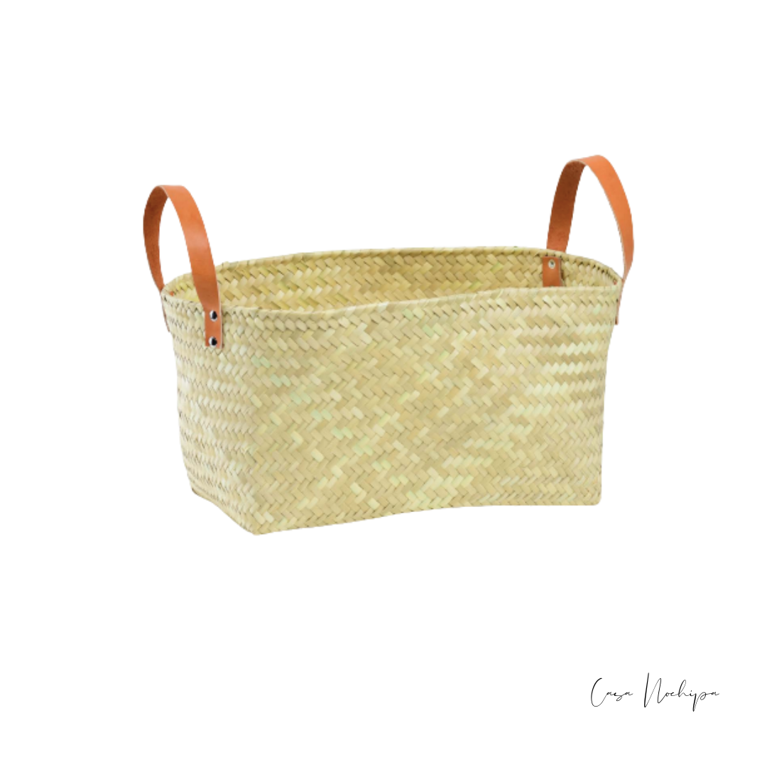 Cesta de palma natural con asas de piel en colores negro y camel, hecha a mano por artesanos mexicanos.