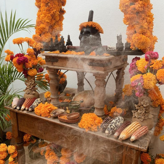 Altar de Día de Muertos decorado con artesanías mexicanas de Casa Nochipa, incluyendo portavelas de barro negro y calaveras pintadas a mano.