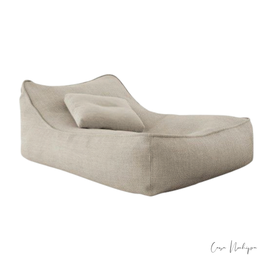 Sillón tipo diván con respaldo suave tapizado en tela Sunbrella color claro.