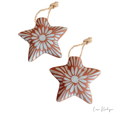 Estrella de barro terracota pintada a mano con flores blancas, ornamento navideño artesanal.