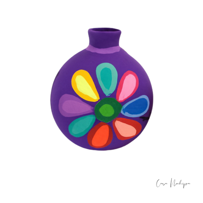 Esfera navideña morada de barro con diseño floral pintado a mano en colores vivos.